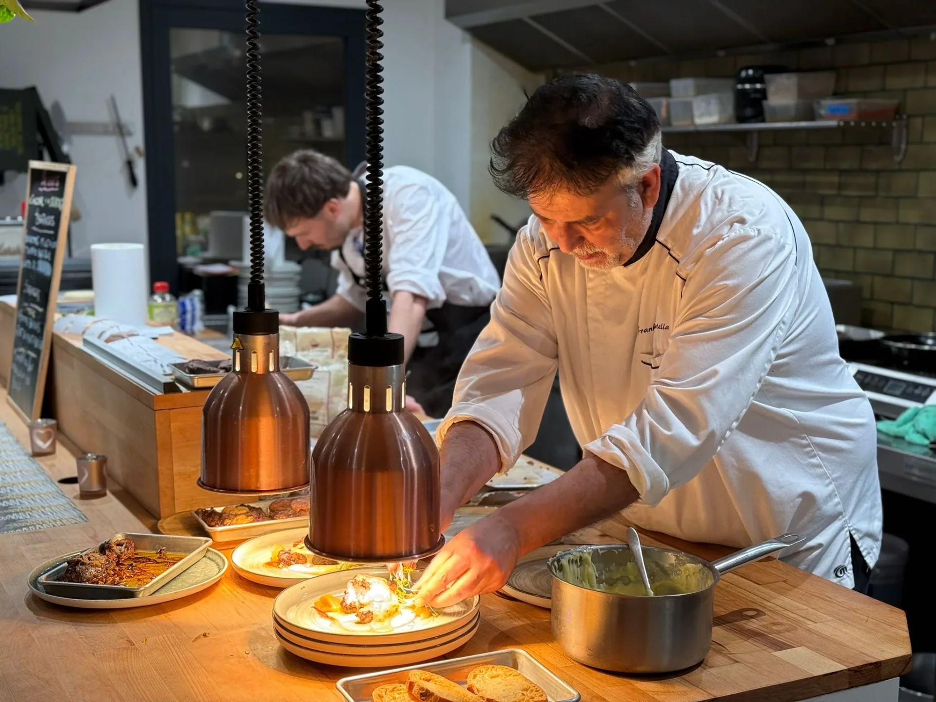 Chef dressant les assiettes dans la cuisine ouverte de La Grange à Marchiennes
